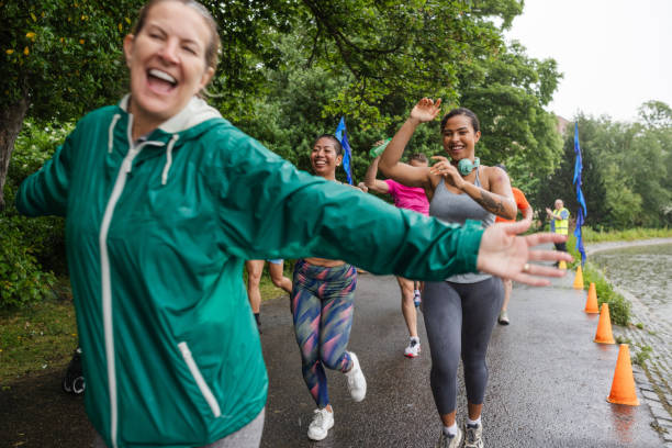 A group of run participants taking part in a fun run in Leazes Park in Newcastle upon Tyne, North East England. Some of them are crossing the starting line and the main focus is one woman looking happy and running with her arms out. The race is open to people of all ages and abilities and is also dog friendly. 

These files have similar videos/images available.